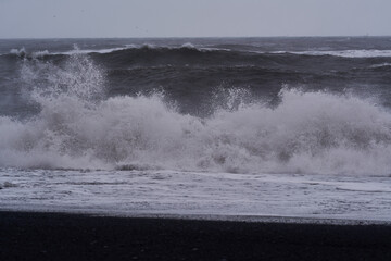 Stormy ocean waves crashing on black sand beach