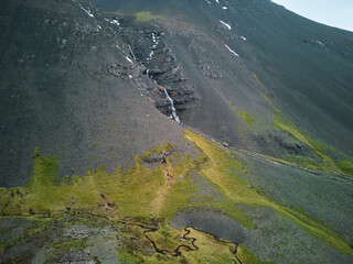 Small waterfall cascading down mountainside in volcanic landscape