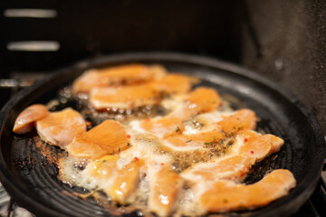 Sizzling salmon fillets on a hot pan ready to be devoured