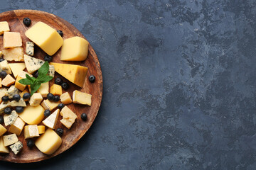 Plate with pieces of tasty cheese on blue background, closeup