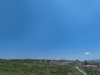 A bright blue sky with a small cloud above a green hillside with houses