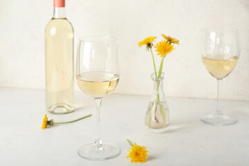 Bottle and glasses of dandelion wine on white table