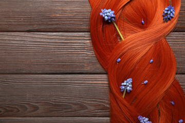 Beautiful ginger hair with Muscari flowers on wooden background, closeup