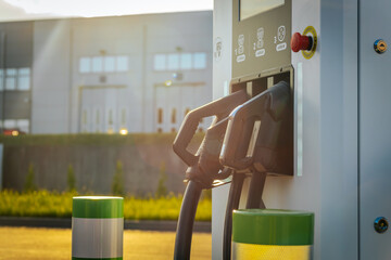 A close up view of three different electric vehicle charging connectors at a charging station,...