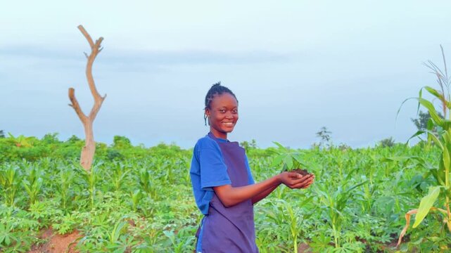 side view copy space 4k footage of youthful african pretty farmer holding up soil dirt with a growing plant 