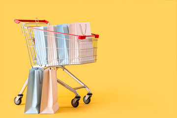 Shopping bags in cart on yellow background