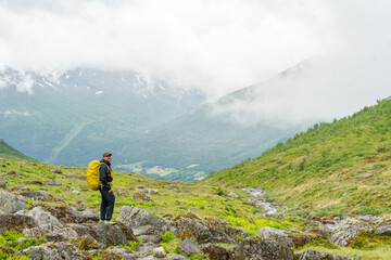 male hiker in the fjord of Andalsnes - Isfjorden in Norway hiking on a rainy cloudy day in the mountains of Massvassbu