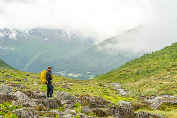 male hiker in the fjord of Andalsnes - Isfjorden in Norway hiking on a rainy cloudy day in the mountains of Massvassbu