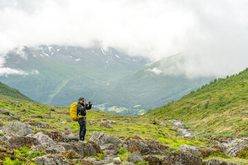 male hiker in the fjord of Andalsnes - Isfjorden in Norway hiking on a rainy cloudy day in the mountains of Massvassbu