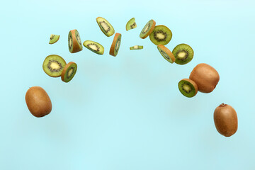 Flying ripe cut kiwi on color background