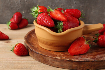 Bowl and board with sweet fresh strawberries on wooden table