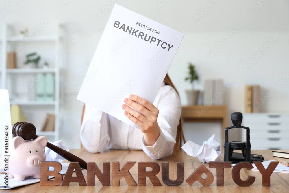 Wall mural Businesswoman with petition and word BANKRUPTCY on table in office