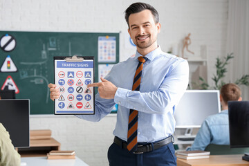 Male instructor pointing at traffic signs in driving school