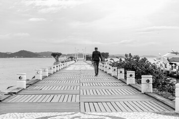 Obraz premium Homeme caminhando sozinha no mole da barra sul de Balneário Camboriú, fine art