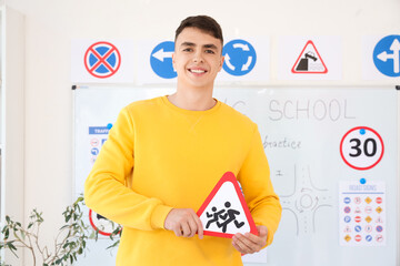 Young man with road sign at driving school