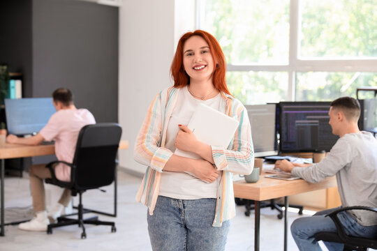 Young female programmer with laptop in office