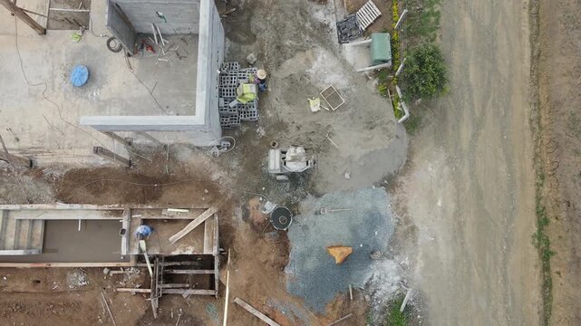 top aerial view of worker adding cement to the mixer in construction site