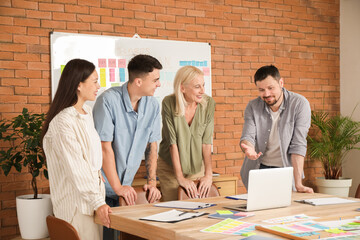Group of people with laptop working on business plan at table in office