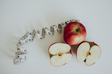 red full and cut in half apples and measuring tape on white background