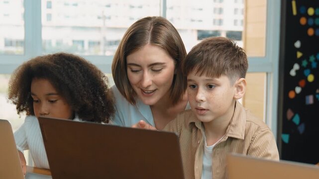 Smart teacher teaching and looking student using laptop at classroom. Professional instructor explained about programing engineering code or prompt while studying and learning program. Erudition.