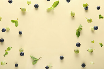 Frame made of berries and mint leaves flying on beige background, closeup