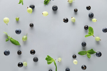Frame made of different berries and mint leaves flying on grey background, closeup