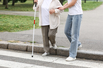 Young woman with blind grandmother crossing road on street