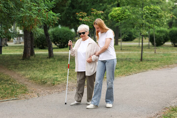 Young woman with blind grandmother walking in park