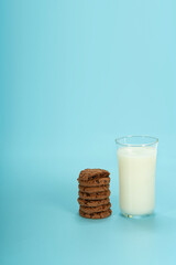 The chocolate chip cookie biscuit with a glass of milk on a blue background. 