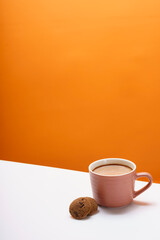 The chocolate chip cookie biscuit with a cup of chocolate drink on a orange background. 