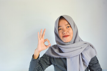 Young cheerful happy smiling pleasant successful employee business woman in her 20s wearing casual brown classic jacket showing okay okay gesture isolated on plain pastel light pink background studio