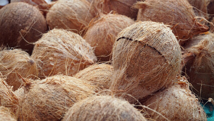 Pile of coconuts at a traditional market. Many pieces of coconut for making virgin oil. Focus selected