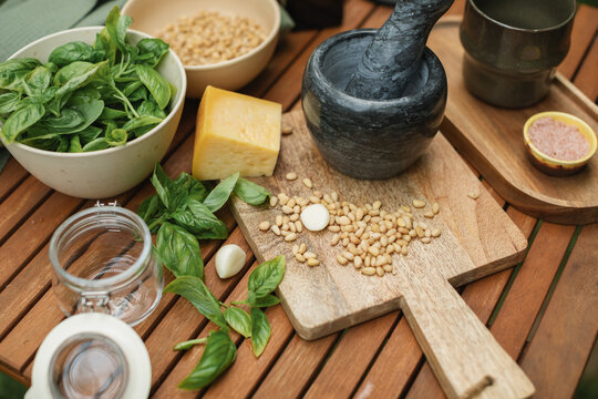 Close-up of basil, parmesan, pine nuts and olive oil on a table for making fresh basil pesto sauce