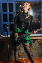 Obraz premium Woman singer playing bass guitar. Band rehearsing at home. International music day.