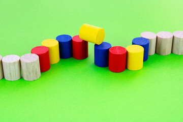 Row of wooden cylinders with different colors where one of them has a different position