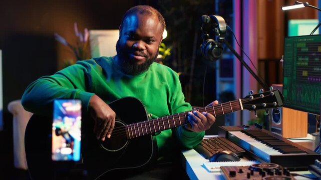 Guitarist instructor hosting guitar lessons online using a mobile phone, recording tutorial for master class. Artist musician explains acoustic instrument accords, assistance for beginners. Camera A.