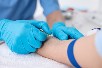 Nurse inserting IV into arm of patient in hospital, closeup