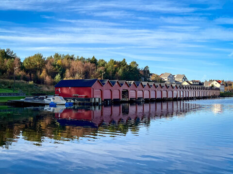 Traditional red timber boathouses along the waterfront, Hellvik Harbour, Eigersund, Rogaland, Western Norway, Norway