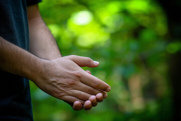 A close-up of a person's hands clapping in a natural green environment.