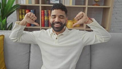 Confident young hispanic man, happy and proud, pointing finger at self in home setting