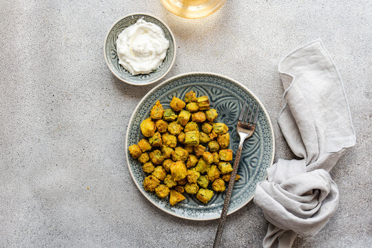 Overhead view of fried okra with a sour cream and garlic dipping sauce and a glass of white wine