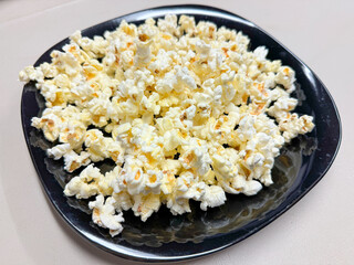 Black plate of freshly popped corn.