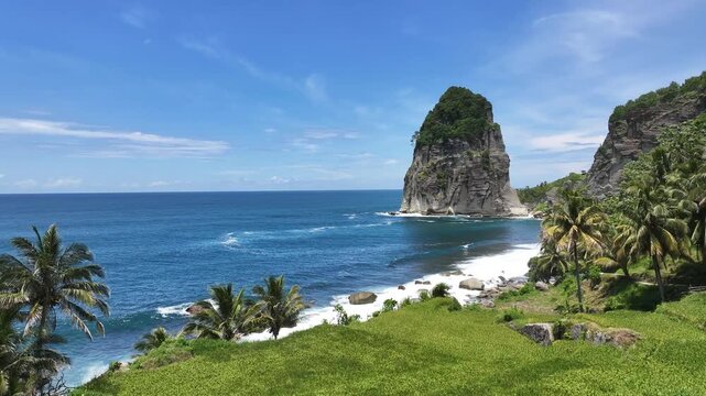 Aerial view of beautiful beach with rice fields and blue sea against the backdrop of large cliffs, Pangasan Beach, Pacitan Regency, East Java, Indonesia