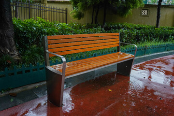 wooden bench standing on the sides of the paved paths of neighbourhood on a rainy day, Chengdu,...