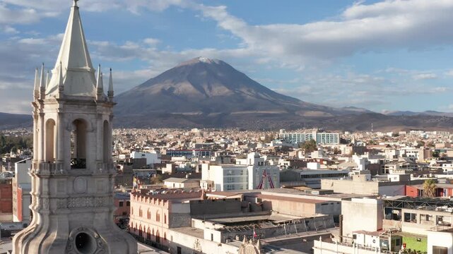 Drone shot of Misti Volcano with reveal of Basilca Cathedral Bell tower in Arequipa, Peru