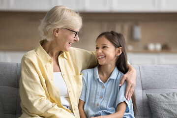 Happy loving grandma hugging happy beautiful granddaughter girl, talking to child, smiling,...