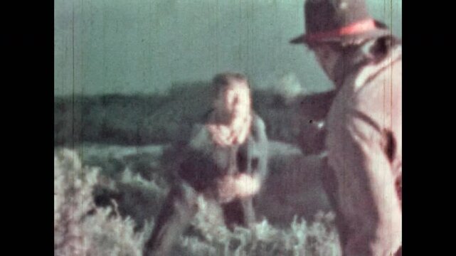 Cowboy shooting man on green hill. Tragic scene from adventure western film in nature outdoor. Cinematic shoot death in wild west,. Villain killing movie hero. Vintage color archive. Retro 1960s