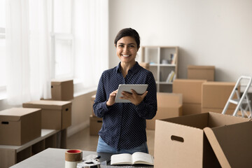 Indian woman using her tablet to check inventory, product availability in warehouse, track incoming...