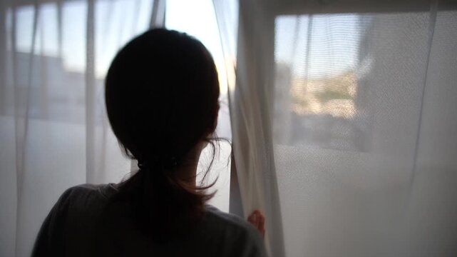 窓から外の風景を見る女性の後ろ姿