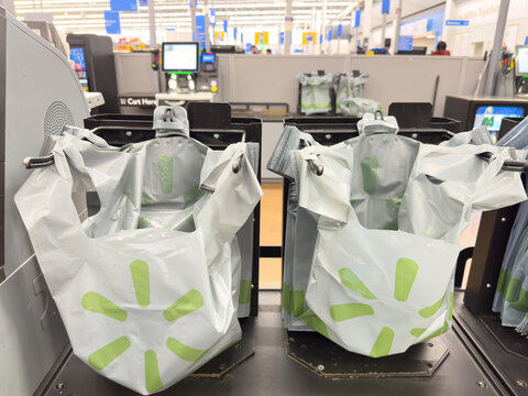Plastic shopping bags at self-checkout station inside Walmart department store.